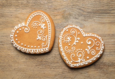 Decorated gingerbread hearts on wooden table, flat lay