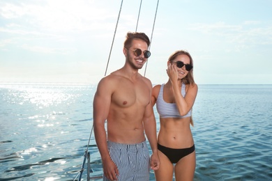 Photo of Young man and his beautiful girlfriend in bikini on yacht. Happy couple on vacation