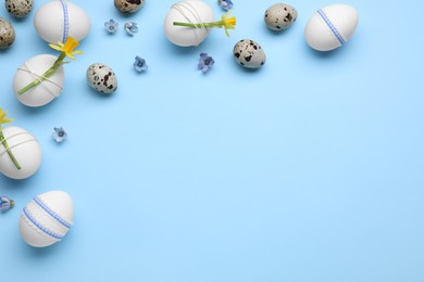 Festively decorated Easter eggs and flowers on light blue background. Space for text