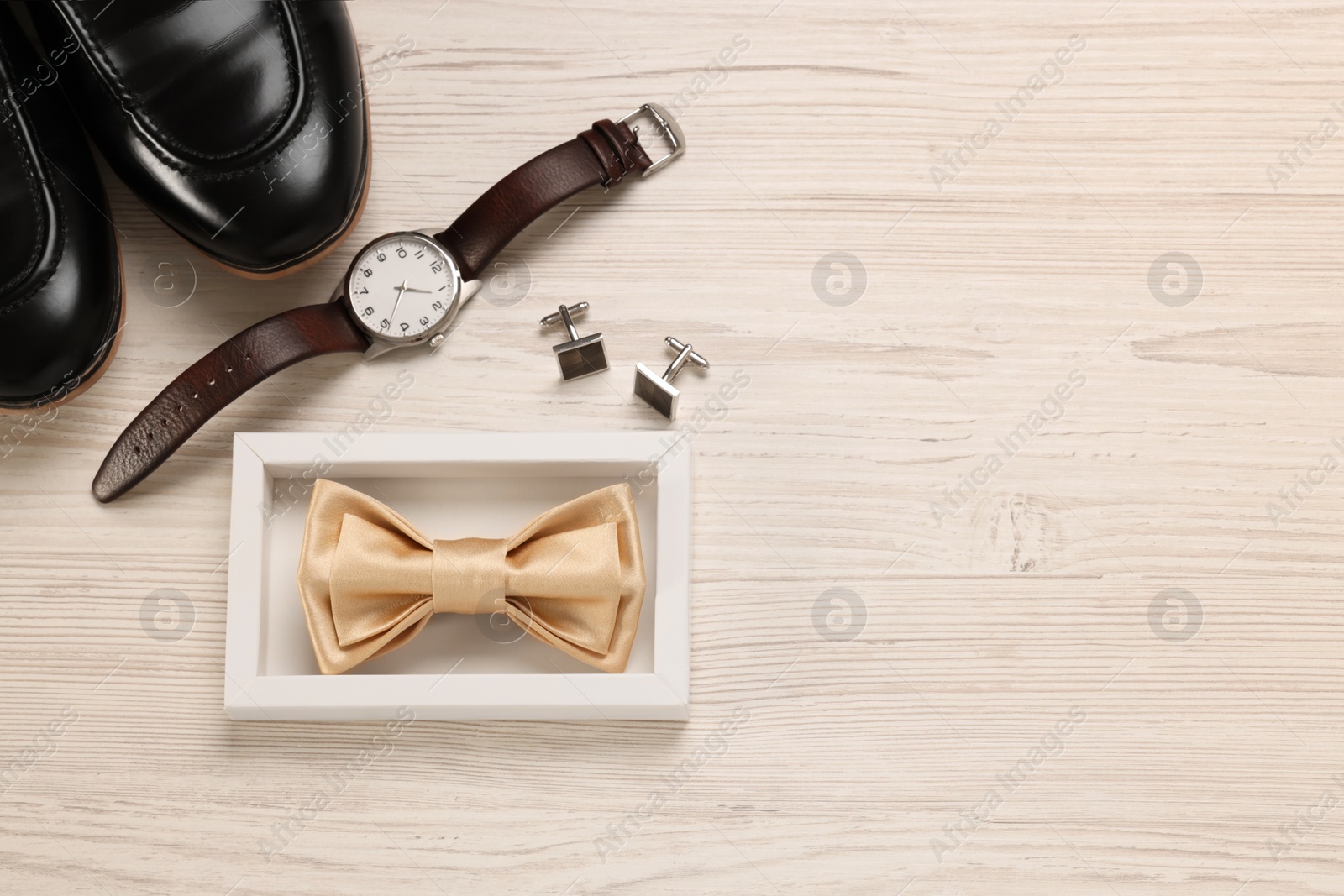 Photo of Stylish beige bow tie, shoes, wristwatch and cufflinks on white wooden background, flat lay. Space for text