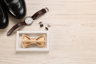 Photo of Stylish beige bow tie, shoes, wristwatch and cufflinks on white wooden background, flat lay. Space for text