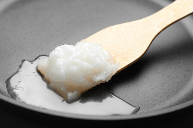 Frying pan with coconut oil and wooden spatula, closeup. Healthy cooking