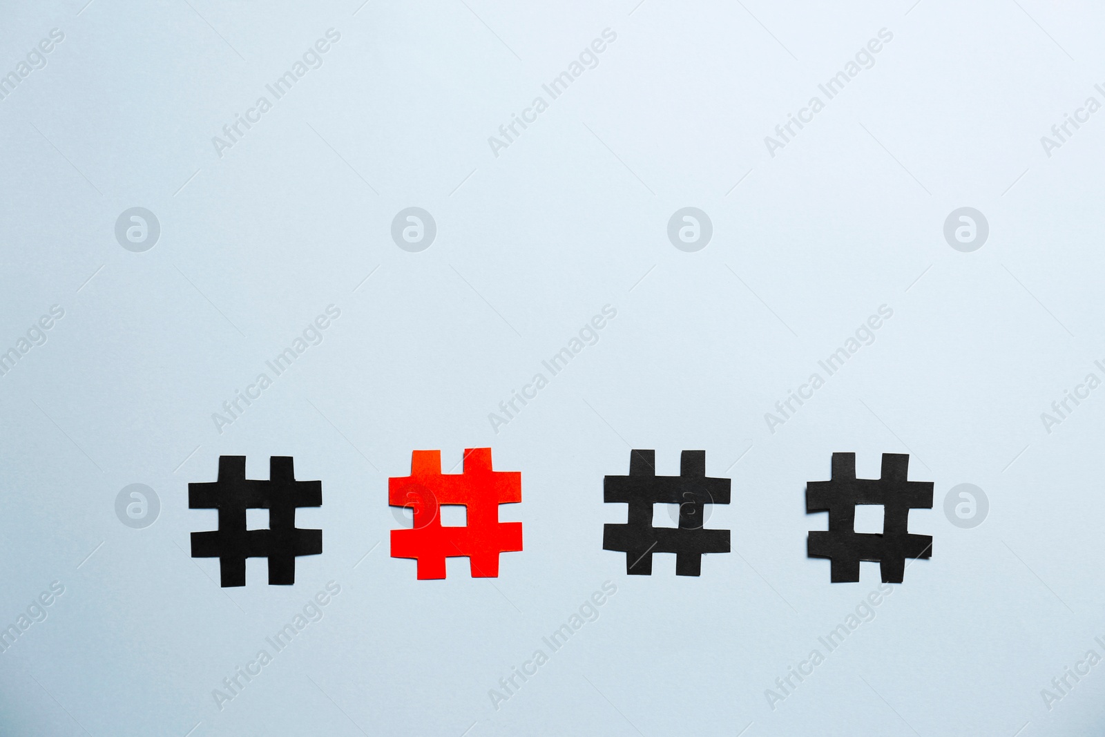 Photo of Red paper hashtag symbol among black ones on light grey background, flat lay. Space for text