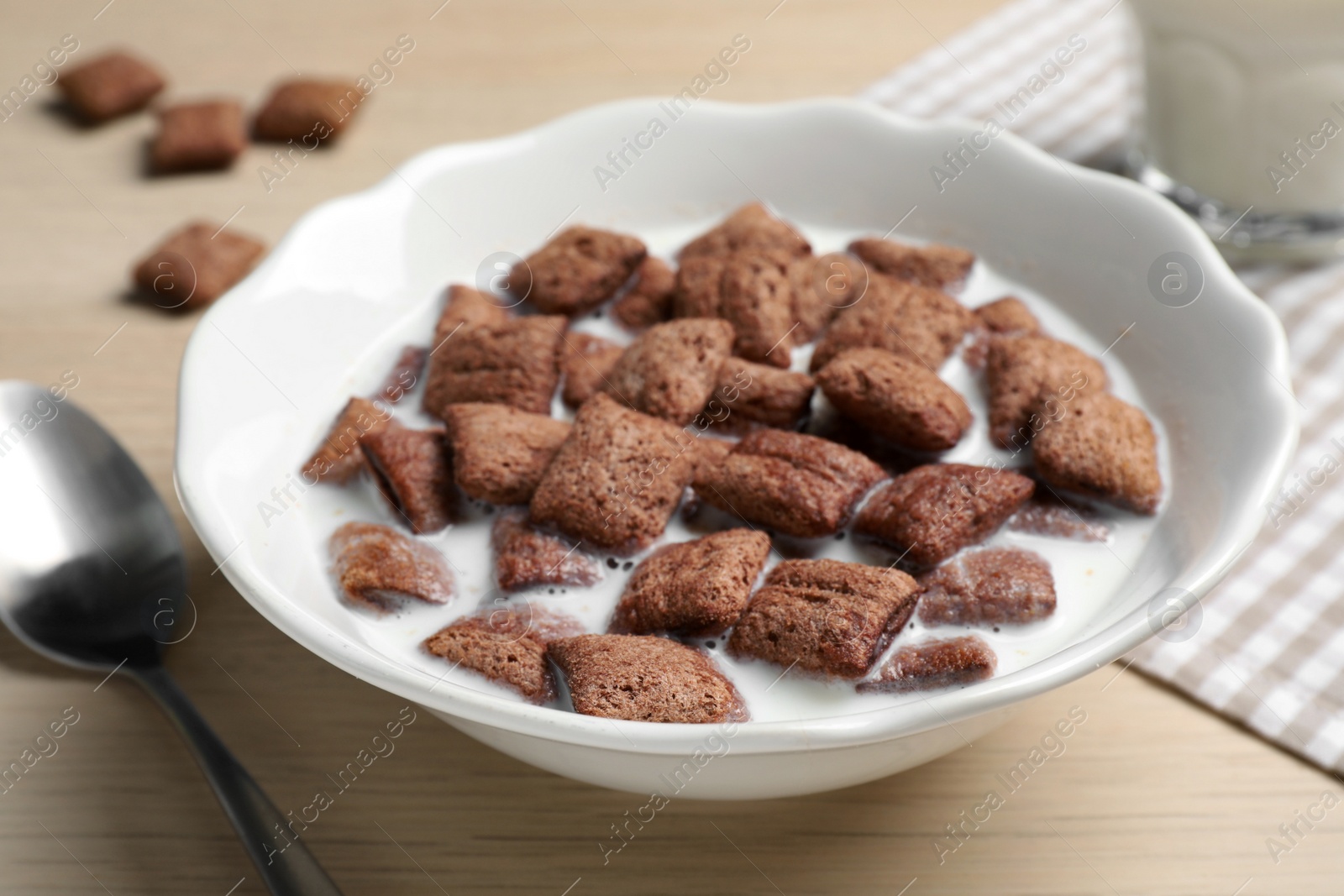 Photo of Bowl with tasty corn pads and milk on wooden table, closeup