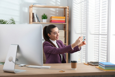 Photo of Lazy employee taking selfie at table in office