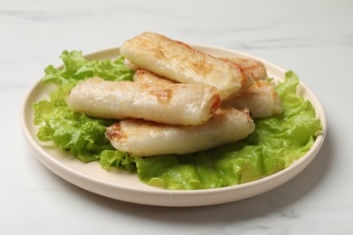 Photo of Delicious fried spring rolls on white table