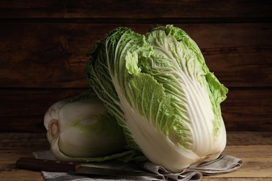 Photo of Fresh ripe Chinese cabbages and knife on wooden table