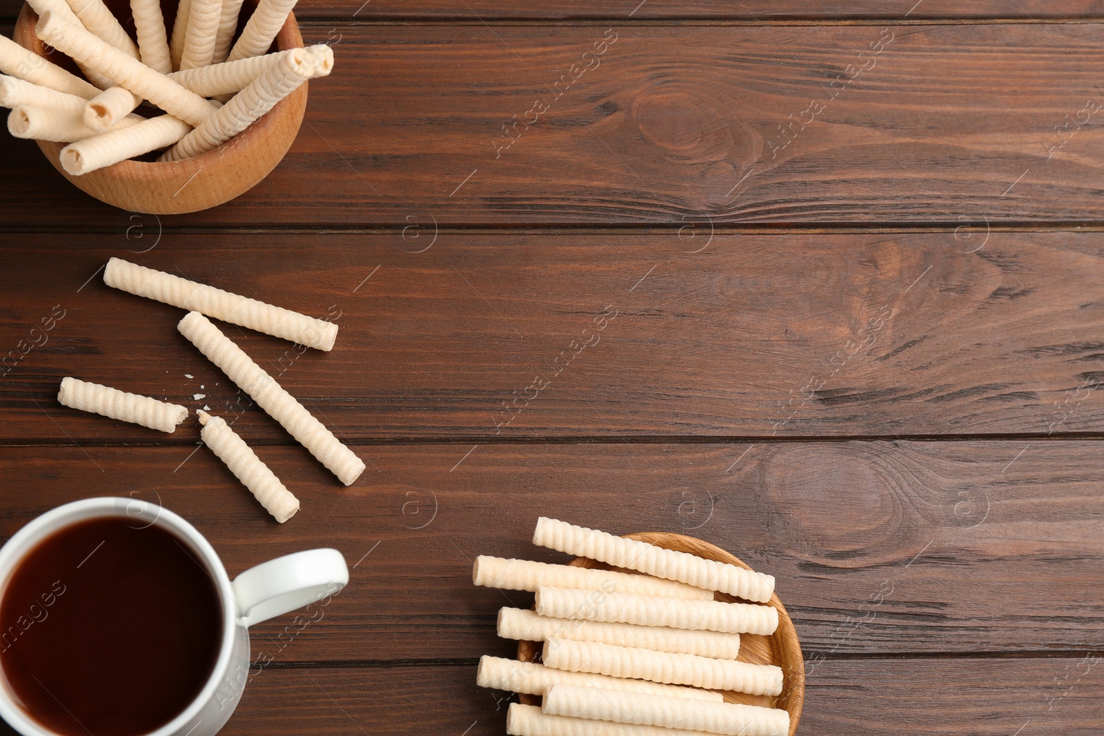 Photo of Flat lay composition with wafer rolls and cup of cocoa on wooden background, space for text