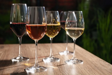 Different tasty wines in glasses on wooden table