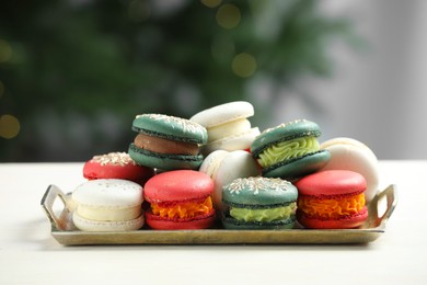 Photo of Different decorated Christmas macarons on white table indoors