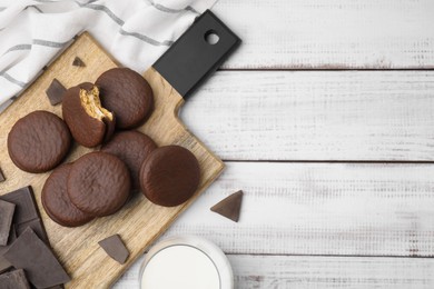 Photo of Tasty choco pies and pieces of chocolate on white wooden table, flat lay. Space for text