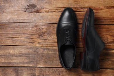 Photo of Pair of black leather men shoes on wooden background, top view. Space for text