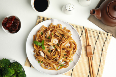 Photo of Tasty buckwheat noodles with meat served on white table, flat lay
