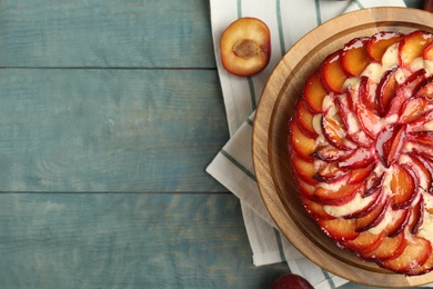 Photo of Delicious cake with plums on blue wooden table, flat lay. Space for text