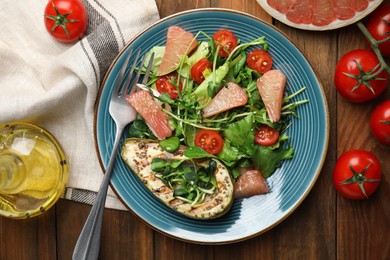 Photo of Delicious pomelo salad with grilled avocado served on wooden table, flat lay