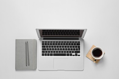 Photo of Laptop, notebook, cup of coffee and pencils on light background, flat lay
