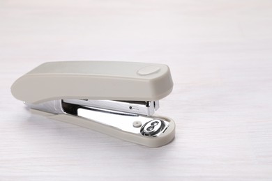 Photo of Beige stapler with staples on light wooden table, space for text