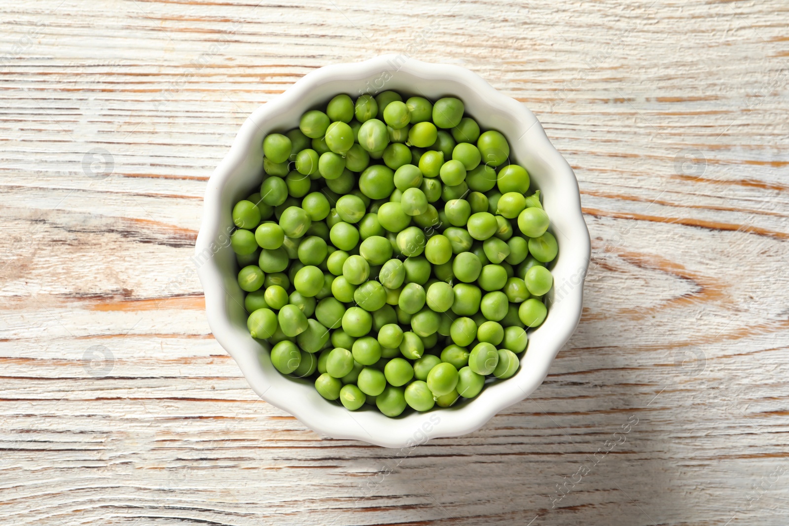 Photo of Bowl with green peas on wooden background, top view