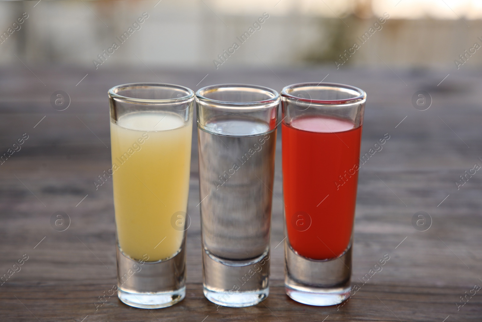 Photo of Shots with lime juice, tequila and sangria as colors of mexican flag on wooden table, closeup. Traditional serving
