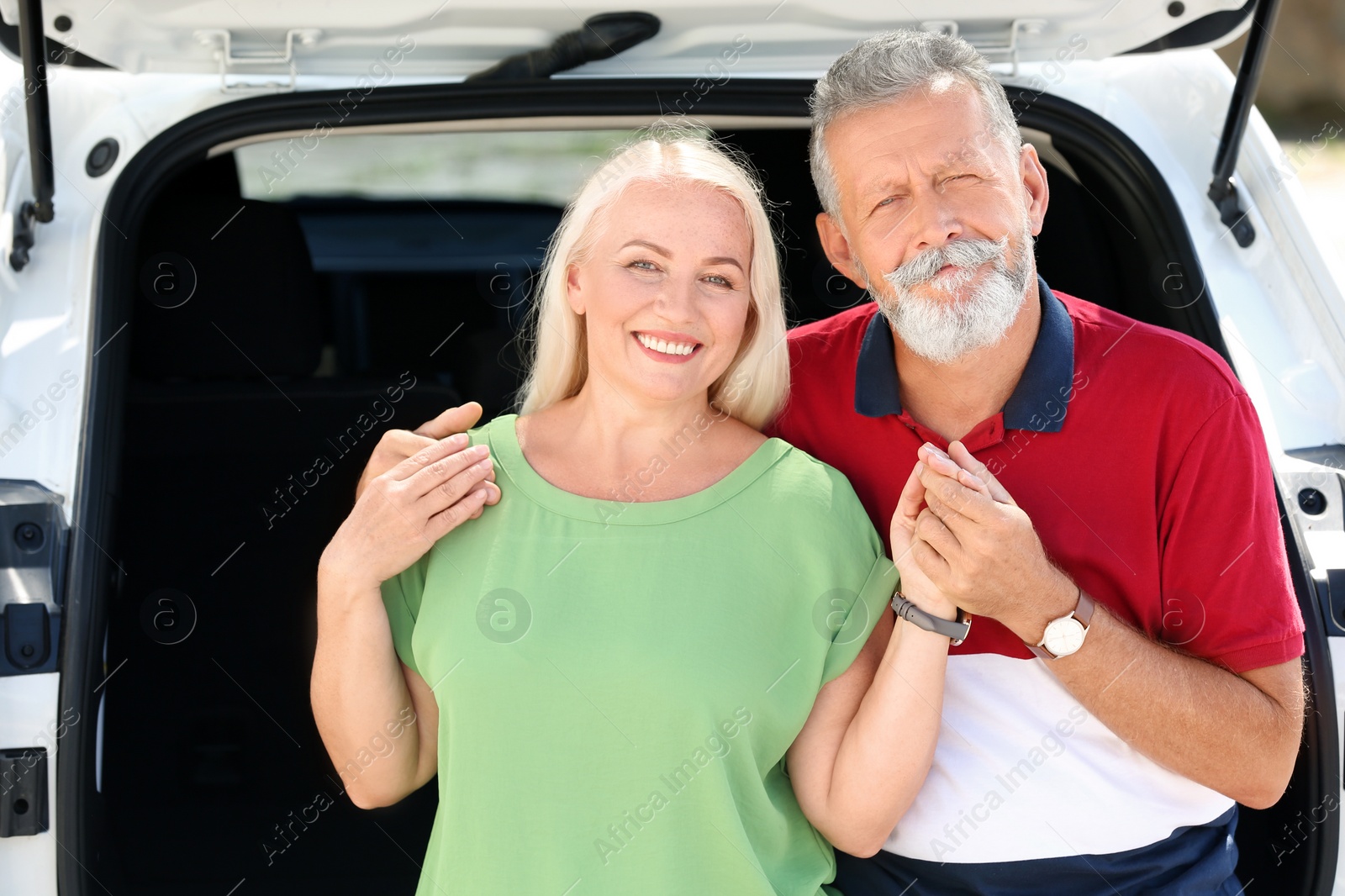 Photo of Happy senior couple sitting in their car trunk outdoors