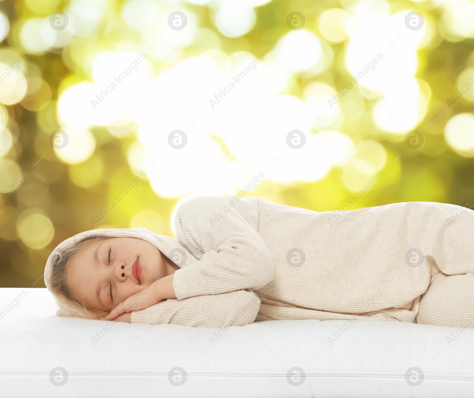 Image of Little girl sleeping on comfortable mattress against blurred green background, bokeh effect. Sleep well - stay healthy