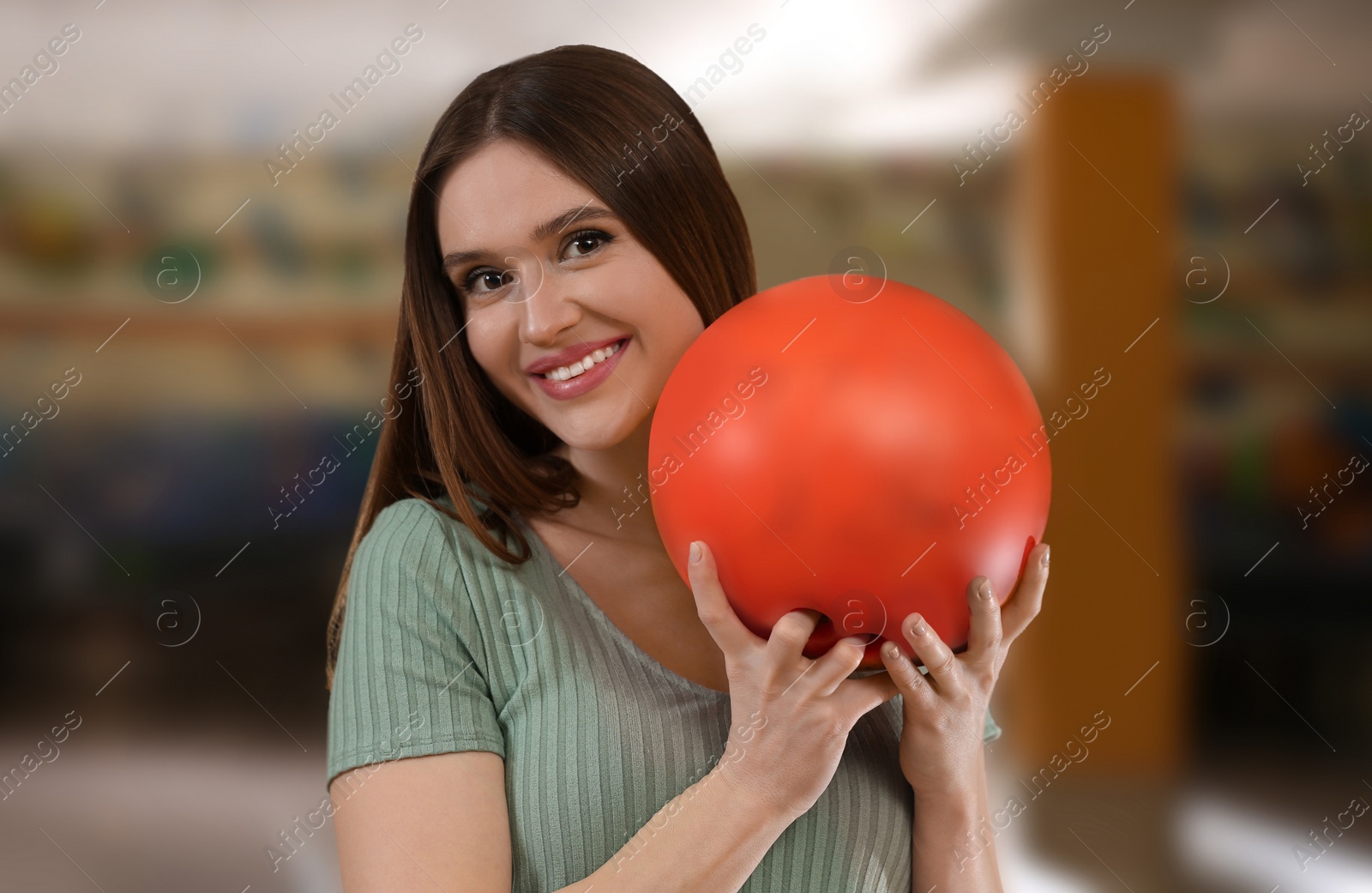 Photo of Young woman with ball in bowling club