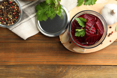 Photo of Delicious pickled beets and spices on wooden table, flat lay. Space for text