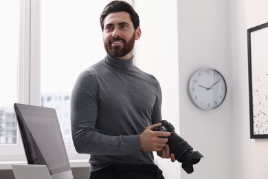 Photo of Smiling professional photographer with digital camera indoors