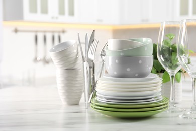 Photo of Many different clean dishware, glasses, cups and cutlery on white marble table indoors. Space for text