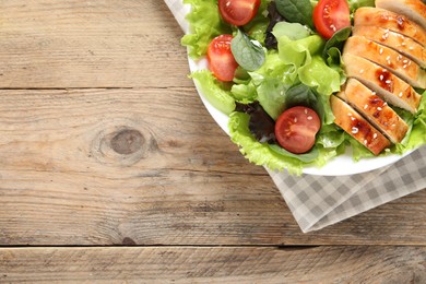 Delicious salad with chicken, cherry tomato and spinach on wooden table, top view. Space for text