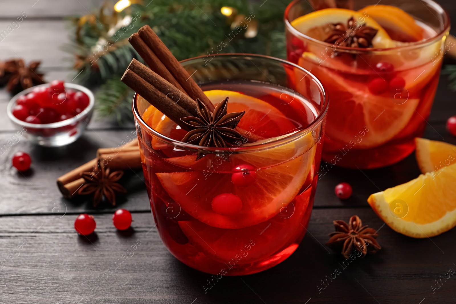 Photo of Delicious punch drink with cranberries, orange and spices on wooden table