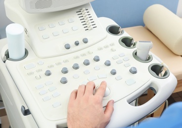 Photo of Sonographer operating modern ultrasound machine in clinic, closeup