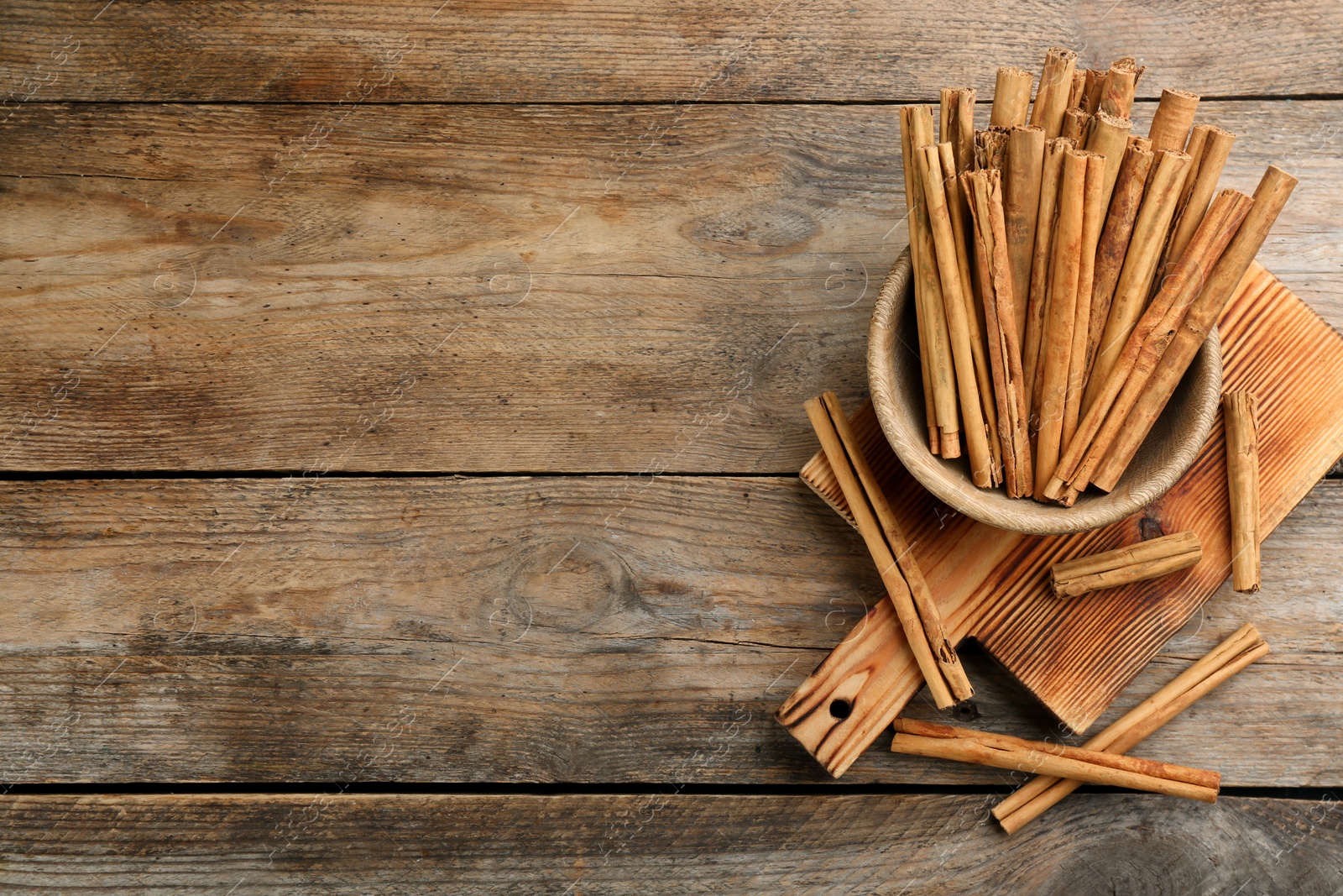 Photo of Aromatic cinnamon sticks on wooden table, flat lay. Space for text