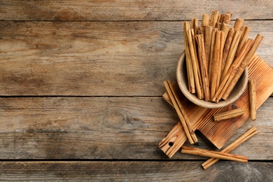 Aromatic cinnamon sticks on wooden table, flat lay. Space for text