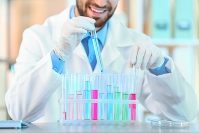 Young scientist working with test tubes in laboratory, closeup. Chemical analysis