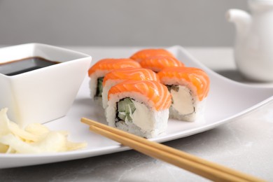Photo of Tasty sushi rolls, soy sauce and ginger on grey table, closeup