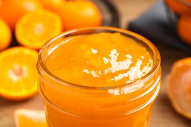 Photo of Delicious tangerine jam in glass jar, closeup