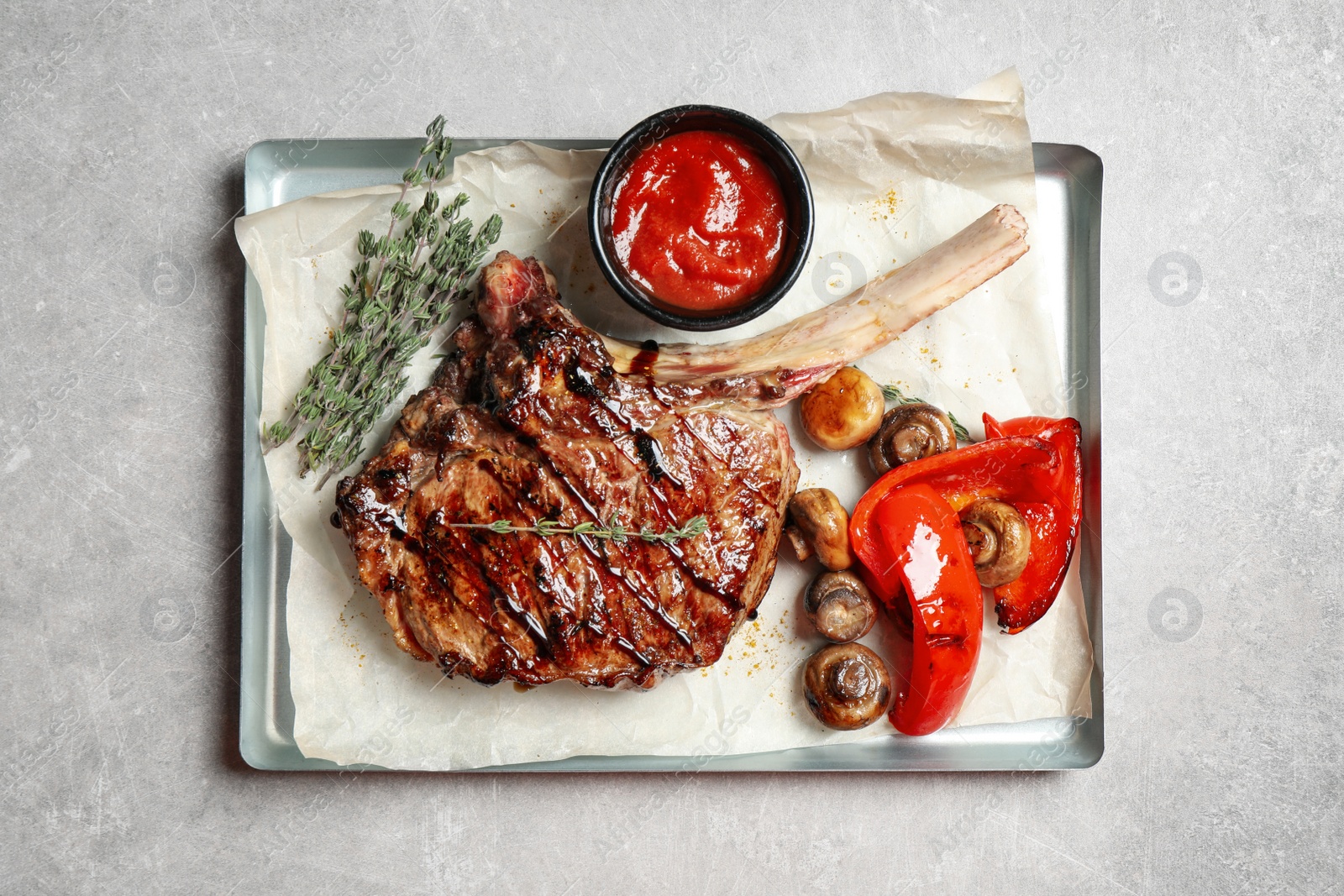 Photo of Delicious grilled ribeye with garnish on light table, top view