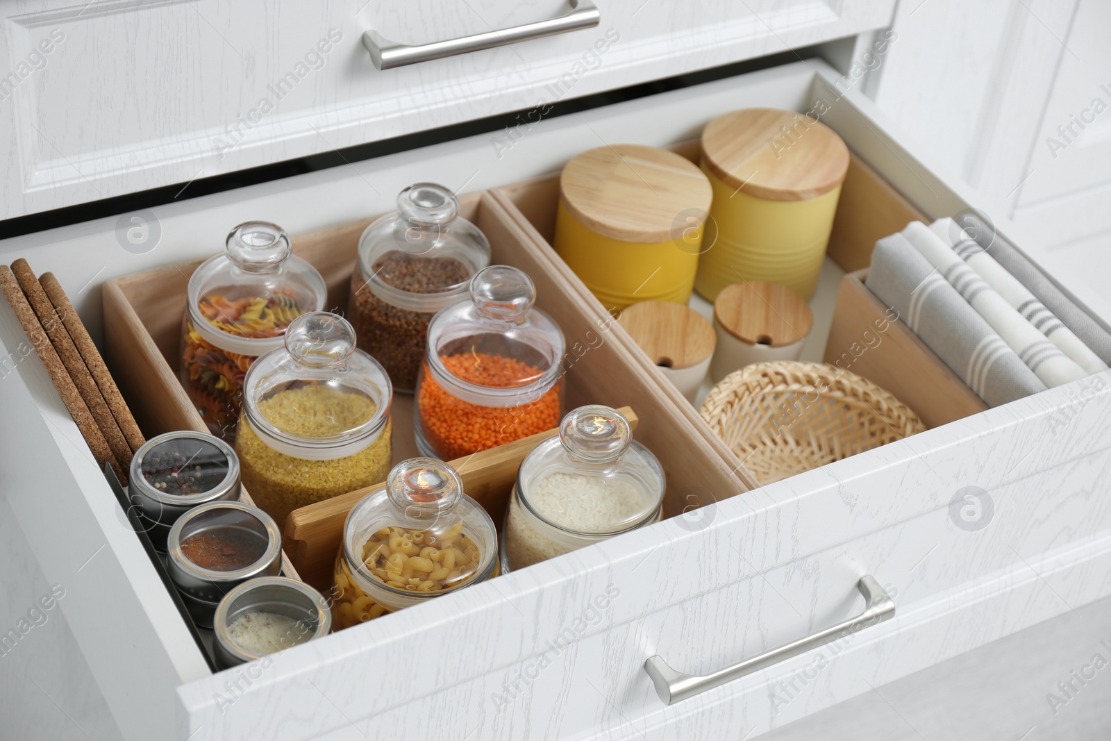 Photo of Open drawer with different jars indoors, closeup. Order in kitchen