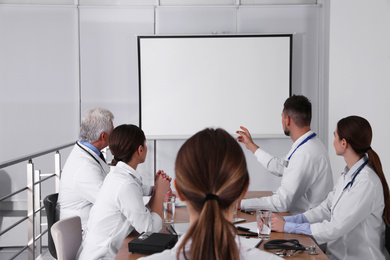 Photo of Team of doctors using video projector during conference indoors