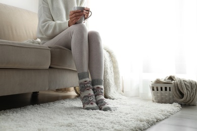 Photo of Woman wearing knitted socks at home, closeup. Warm clothes