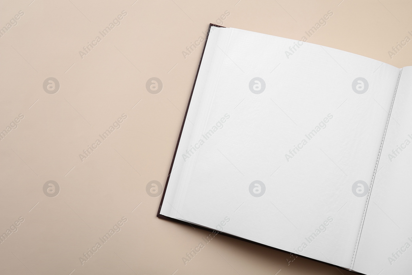 Photo of Open photo album on beige background, top view. Space for text