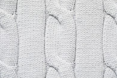 Photo of Texture of soft light knitted fabric as background, top view