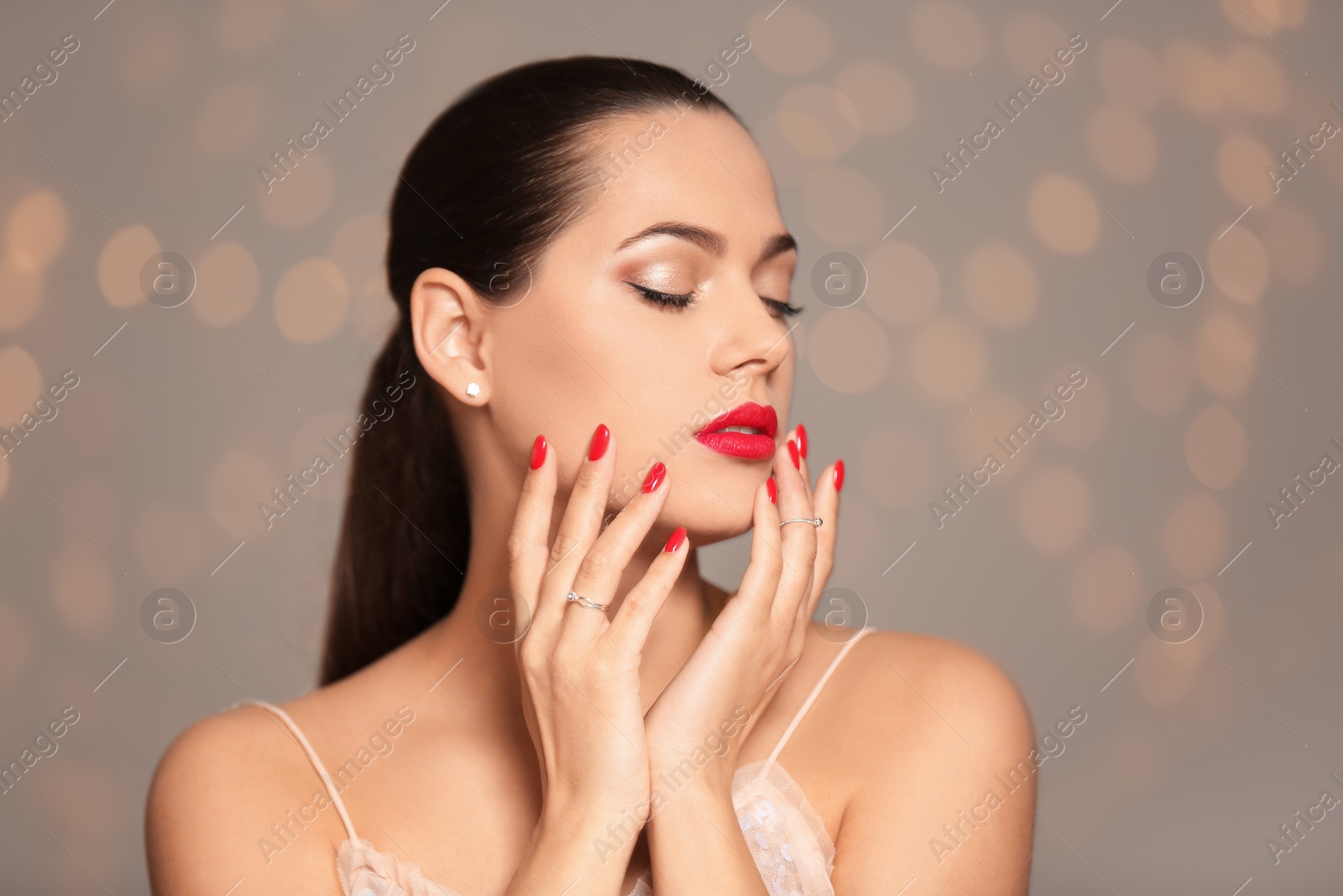 Photo of Portrait of beautiful young woman with bright manicure on blurred background. Nail polish trends