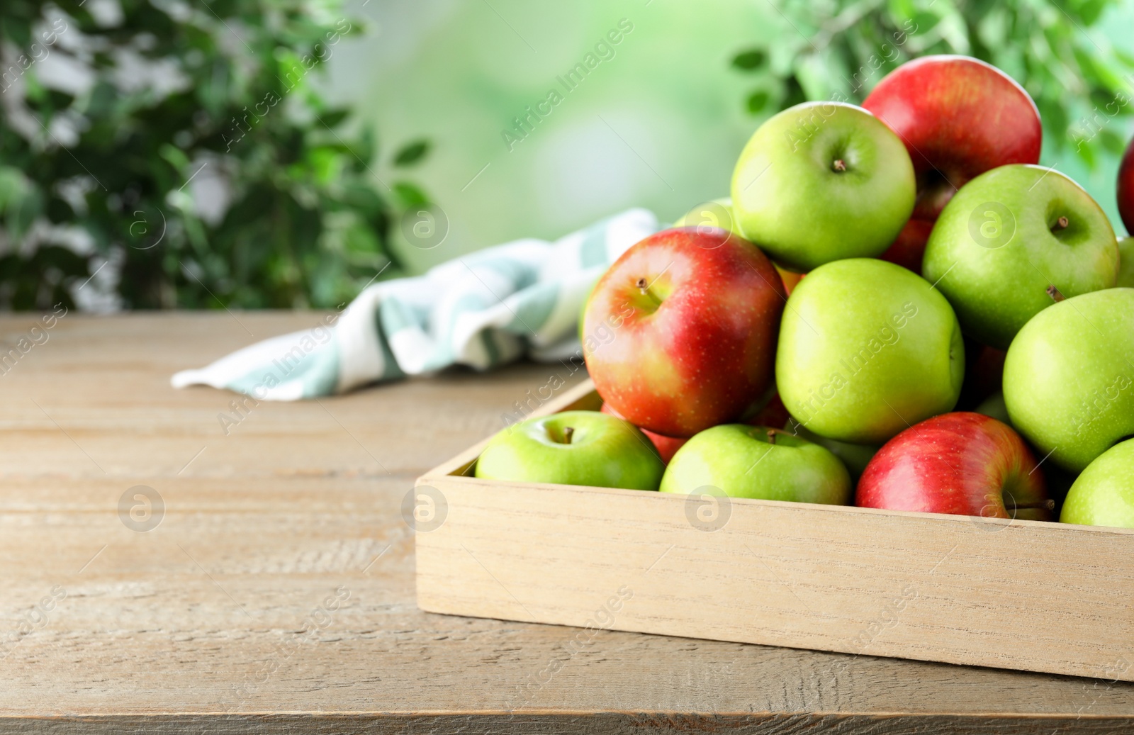 Photo of Ripe apples on wooden table against blurred background. Space for text