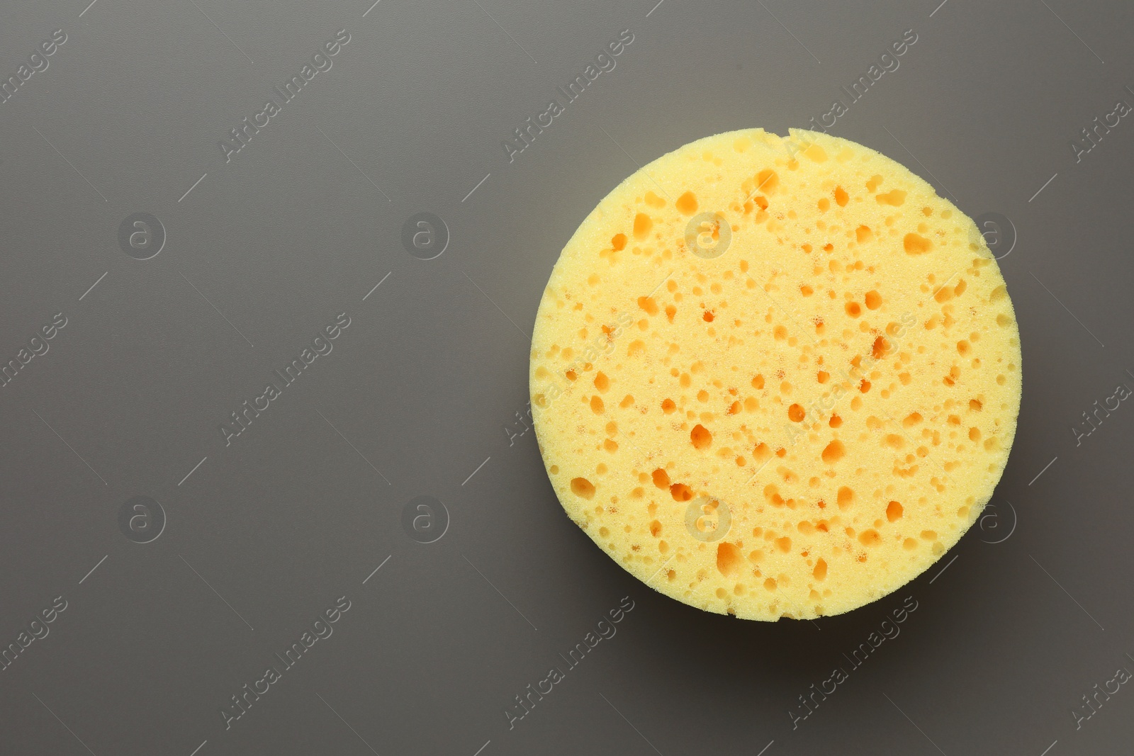 Photo of New yellow sponge on grey background, top view. Space for text