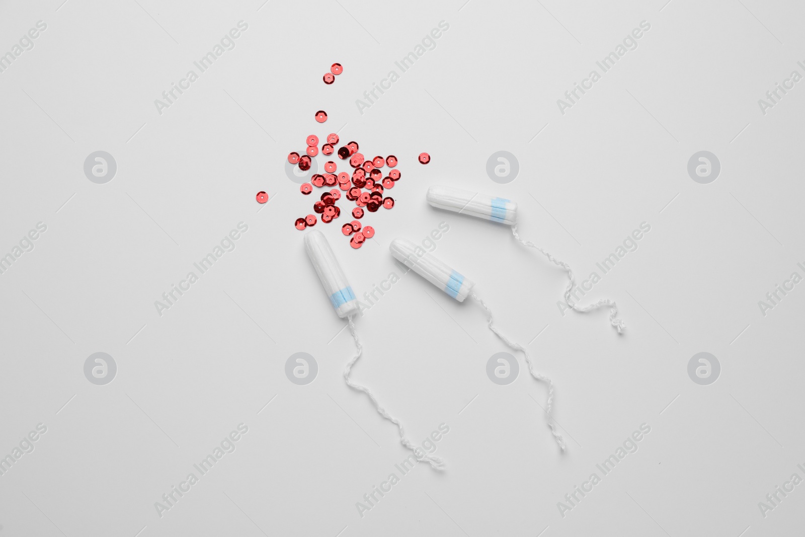 Photo of Tampons and red sequins on white background, flat lay. Menstrual hygiene product