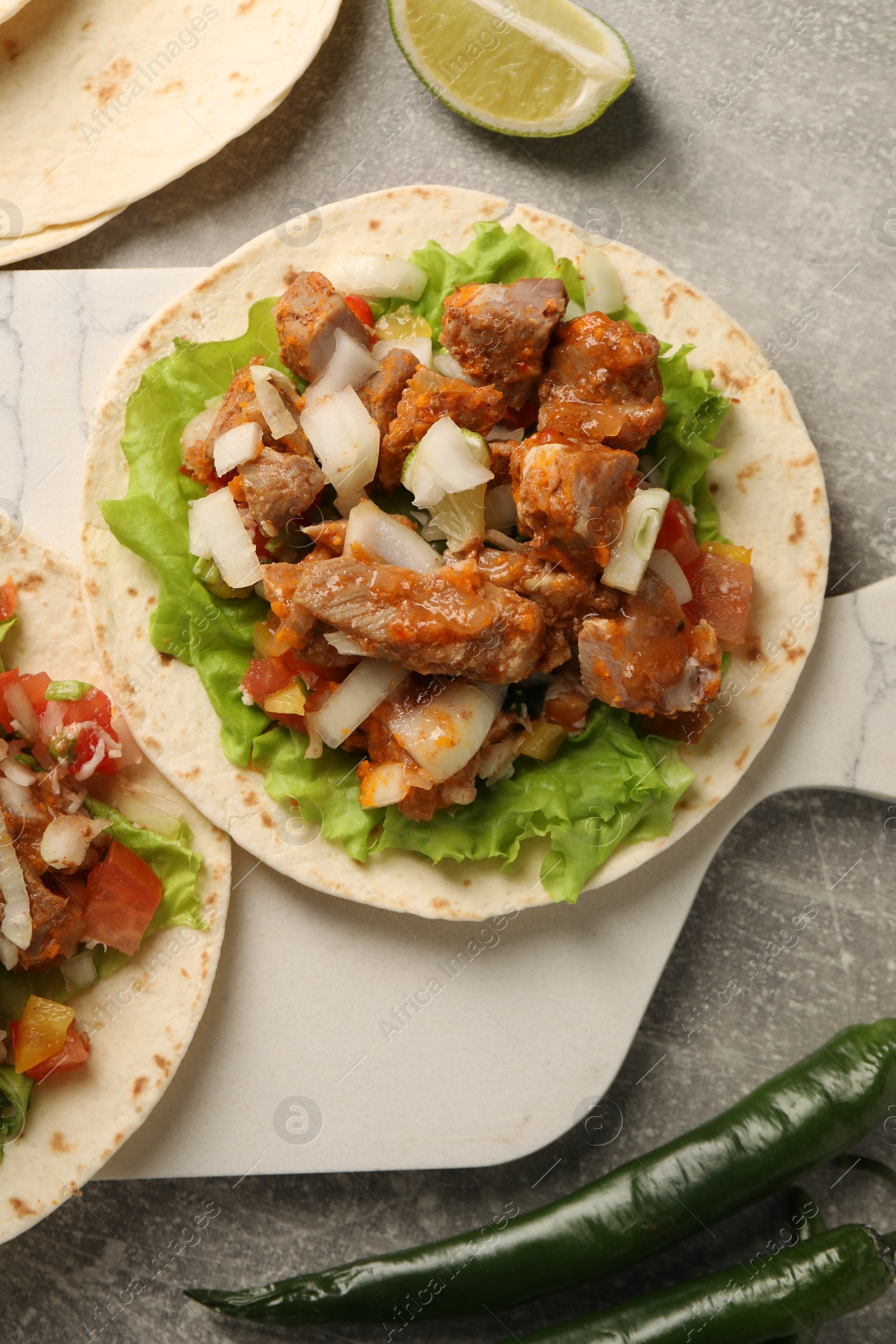 Photo of Delicious tacos with vegetables and meat on grey textured table, flat lay