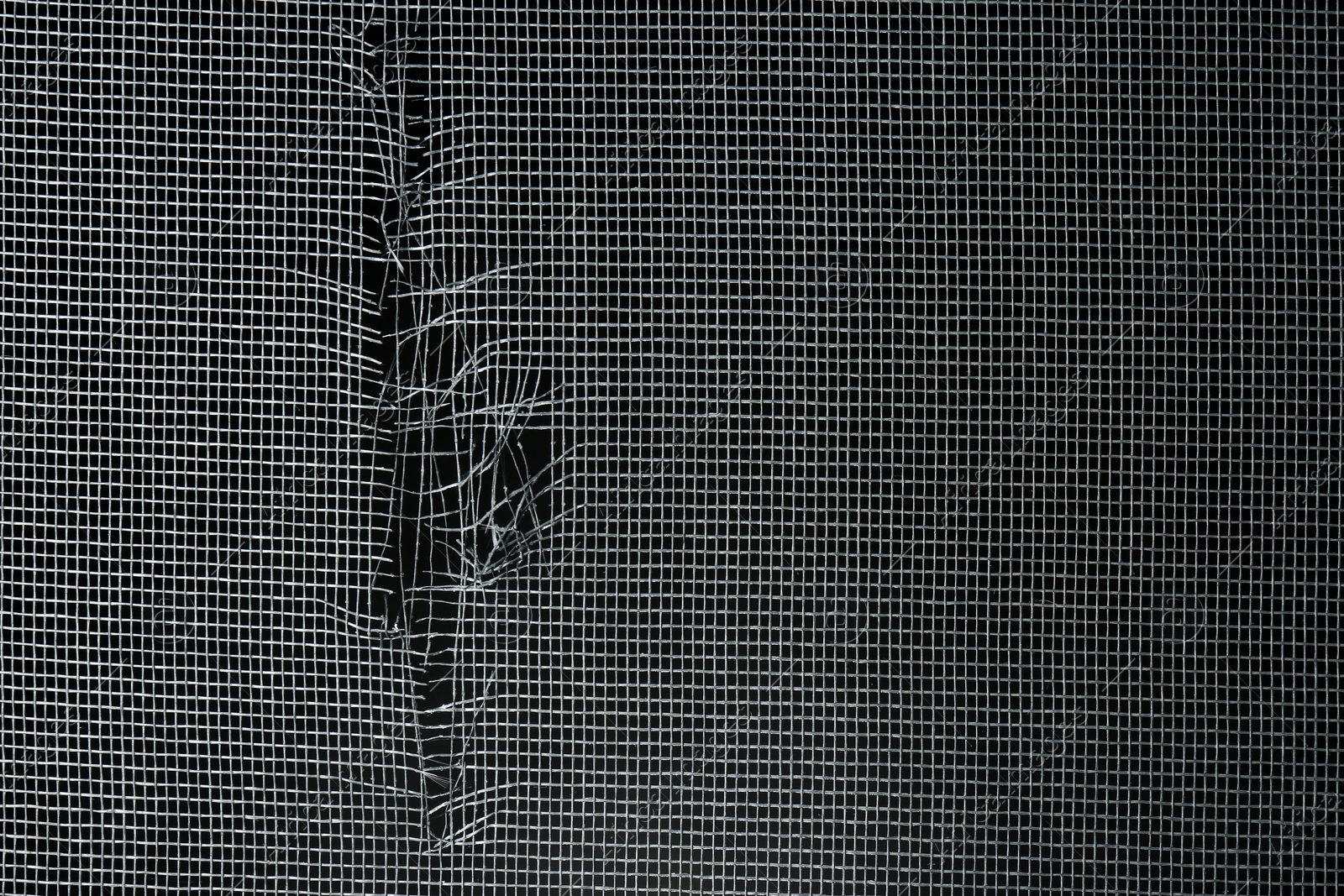 Photo of Torn window screen against black background, closeup