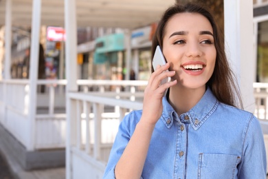 Photo of Young woman talking by phone outdoors on sunny day